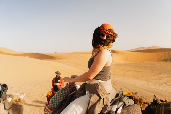 Merzouga Sunsets - Day 5 Morocco Uncovered TruTravels Female traveller in Morocco poses on a sunset camel ride in Morocco
