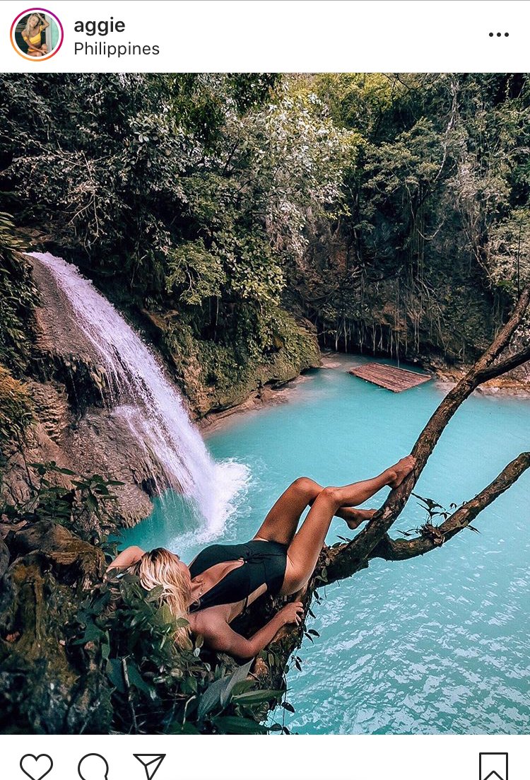 Girl laying on tree looking out to waterfall and trees
