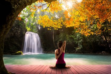 A woman practicing yoga by a picturesque blue waterfall 