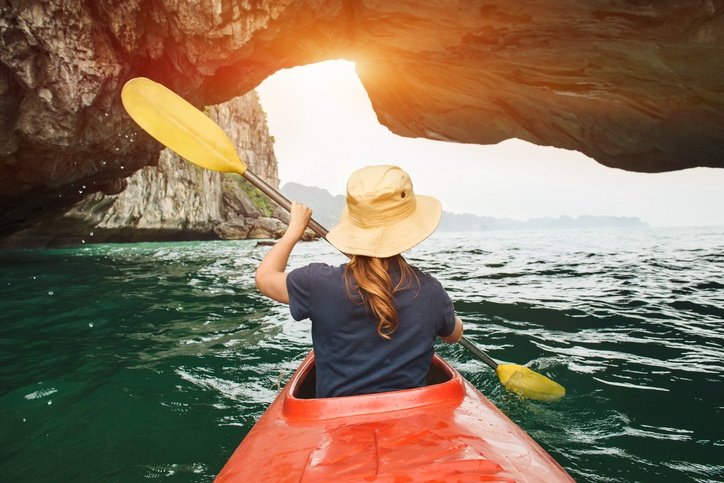 Woman explore Ha Long Bay on kayak with limestone mountains on background. Ha Long Bay, Vietnam, Cat Ba Island