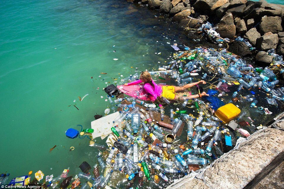 girl swimming in the sea surrounded ocean plastic / waste
