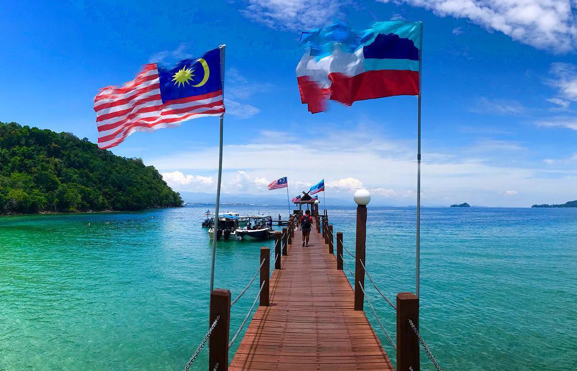View of the sea and jetty with Malaysian flag and people walking down