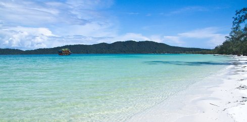 A scenic photo of Koh Rong Sanloem in Cambodia showing the crystal clear blue sea, white sand beach and lush green landscape