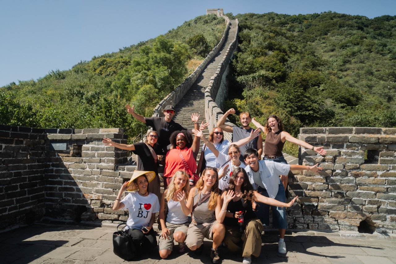 Group of young travellers cheering with arms raised on the Great Wall of China on the TruTravels Wonders of China tour