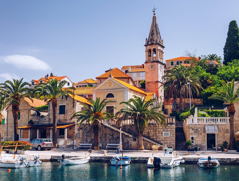 The island of Brac in Croatia showing the incredible architecture, palm trees along the waterfront and boats on the water