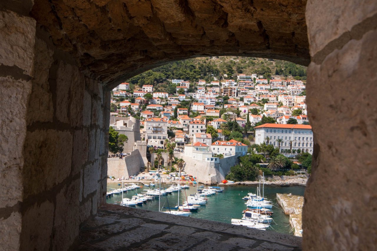 A scenic photo of Dubrovnik, Croatia through a window with the marina and picturesque town in view