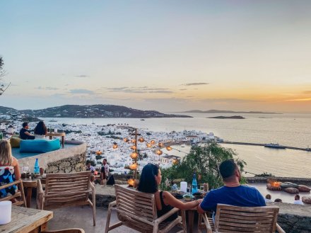 A photo of Mykonos at sunset, overlooking the white villas, the harbour and mountains