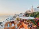 A view of the white and orange villas at sunset in Oia, Santorini, Greece