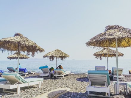 A photo of the beach in Kamari, Santorini, Greece with sun loungers, umbrellas and the sea in view