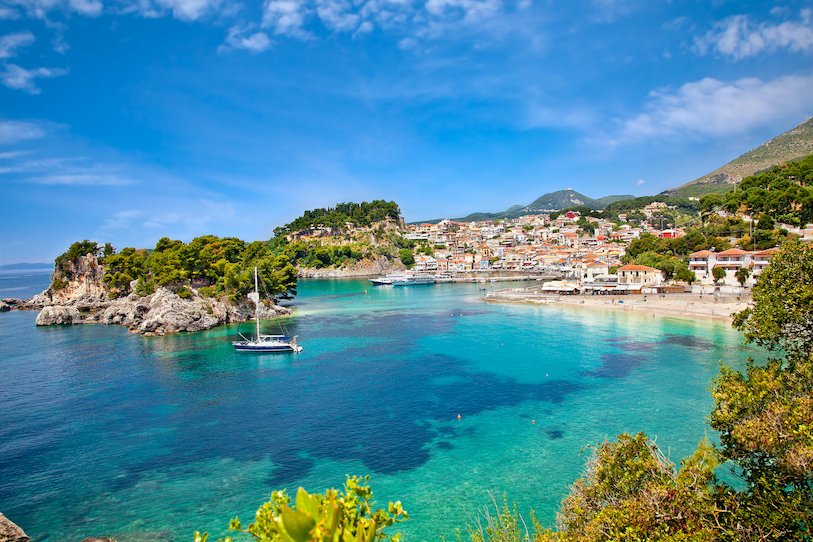 A scenic view of the coast, bright clear blue water and houses along the waterfront in Syvota, Greece