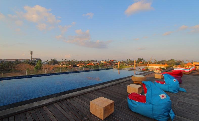 Blue sky rooftop pool with bean bags around