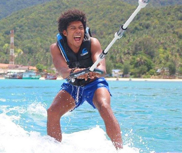 Man wake boarding surrounded by blue sea and green hills