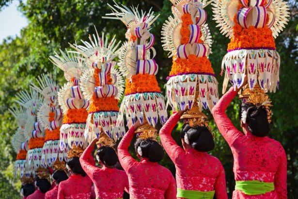 Local asians holding large colourful head ornaments 