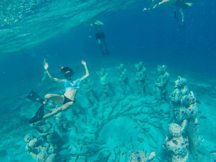 Girl underwater snorkelling with statues around