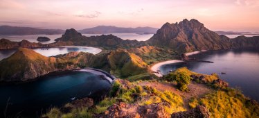 View of Komodo islands surrounded by dark sea with pink sky