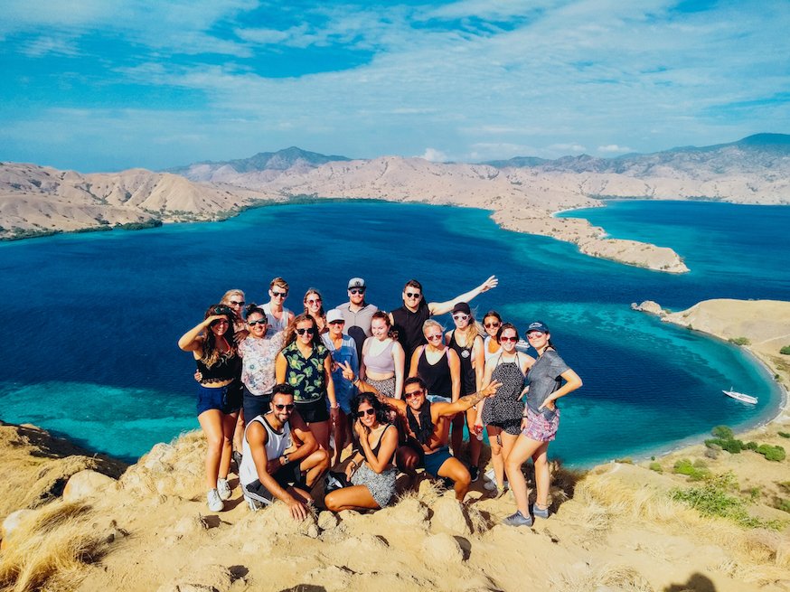 Group of travellers standing at the top of Padar view point with blur sea and hills in background