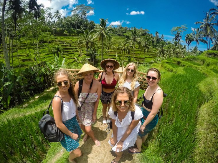 group of girls at rice terraces in ubud bali with blue sky and green palm trees in background