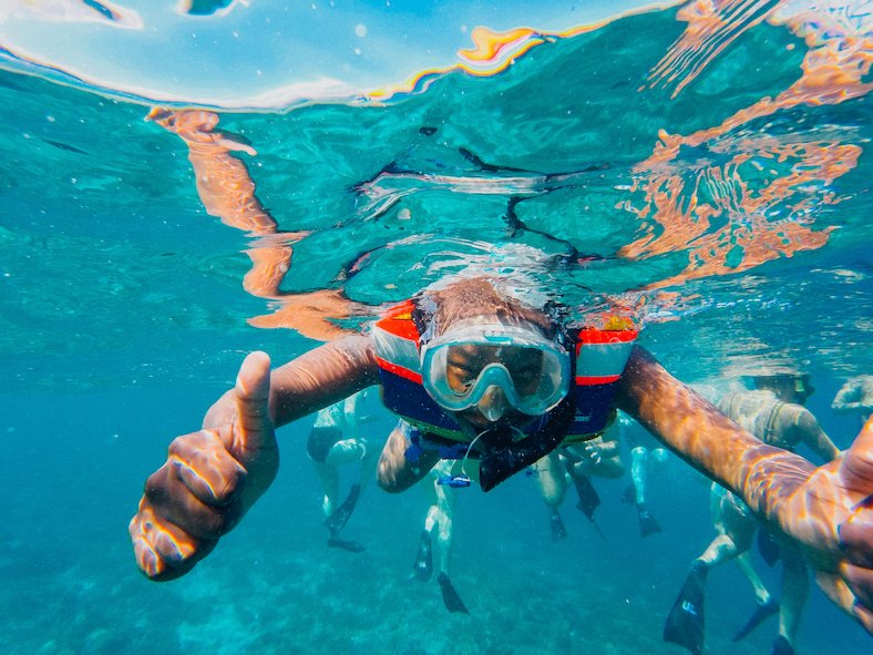 Man underwater wearing snorkel maske and lifejacket looking at camera