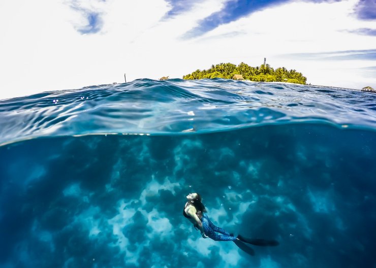 A split-level shot of someone snorkelling in the blue ocean 