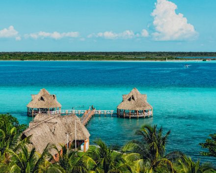 A scenic shot of two huts and a jetty in the stunning bright blue clear ocean in Bacalar, Mexico 