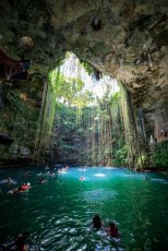 A shot of a turquoise blue Cenote in Mexico with people swimming in the water 