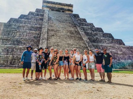 A group of people posing in front of the glorious wonder of the world Chichen-Itza