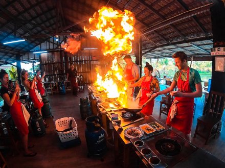 A group experimenting with flames in the wok at a cooking class in Chiang Mai Thailand 