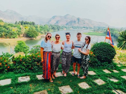 group of young people standing with beautiful scenery of lakes and mountains in the background in Thailand