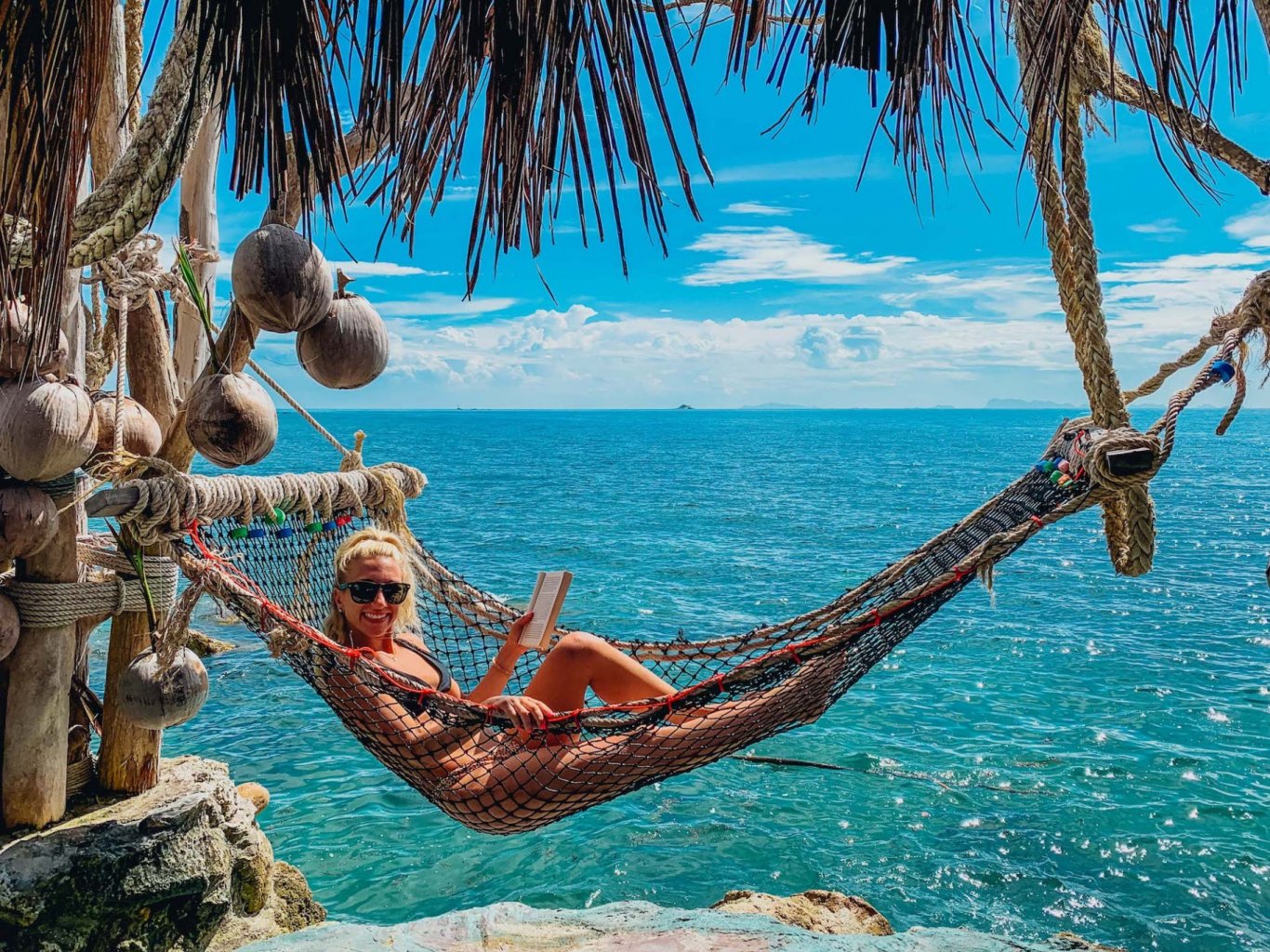 A picturesque photo of a girl on a hammock by crystal clear blue waters in Koh Phangan Thailand