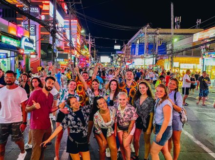 large group of friends on a night out in Phuket with lots of colours from shops and bars in the background