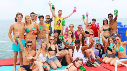 large group of people on a boat holing beers in the air in Thailand