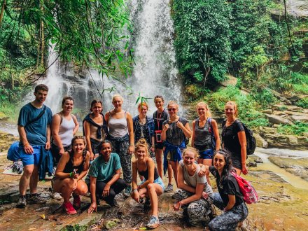 A group photo in front of a waterfall during the jungle trek in Northern Thailand 