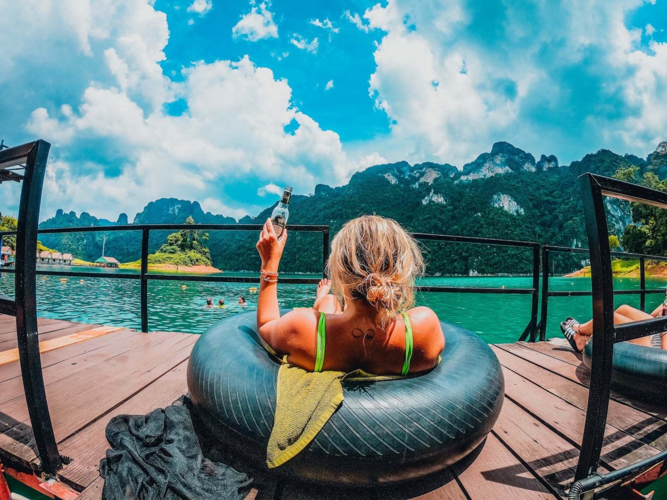 A girl in a doughnut holding a beer and admiring the view of Khao Sok in Thailand 